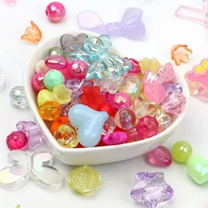 Detailed view of mixed colorful acrylic beads in heart-shaped bowl for DIY jewelry