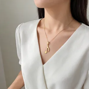Nahaufnahme einer eleganten Gold-Musiknoten-Halskette, die von einem Model getragen wird