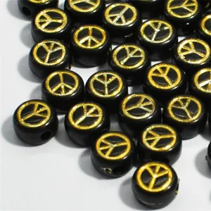 Macro view of 7mm black acrylic beads featuring golden engraved peace sign symbols