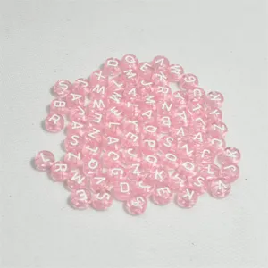 Primer plano de cuentas de letras de acrílico rosa de 7mm para crear bisutería.