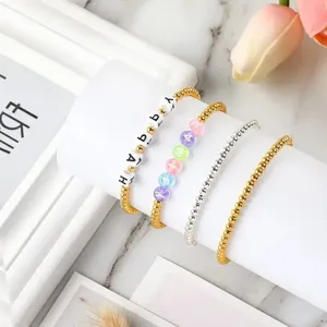Primer plano de pulseras DIY con cuentas de metal en oro y plata y cuentas de letras
