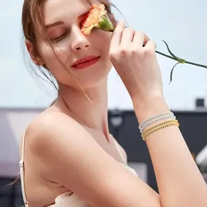 Modelo con pulseras de cuentas espaciadoras redondas de metal en oro y plata a la luz