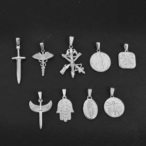 Detail of various stainless steel vintage pendants including sword, Hamsa, and wings.