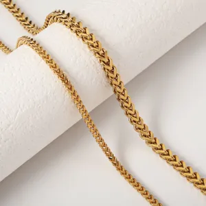 Close-up detail of a gold-toned stainless steel wheat chain necklace