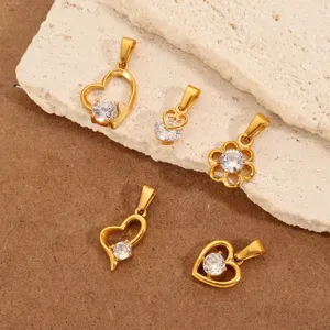 Detailopname van vintage 18k vergulde hangers met hart en bloem en heldere zirkonia