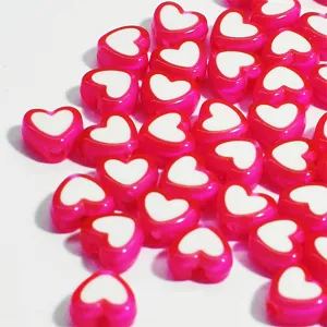 Detalle macro de cuentas de acrílico rosa de 8mm en forma de corazón con centro blanco