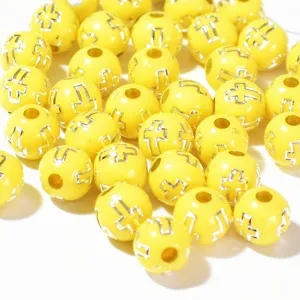 Détail macro de perles en acrylique jaunes de 8 mm avec croix argentées pour bijoux