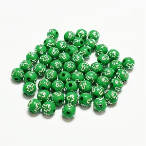 Détail macro de perles acryliques vert clair de 8mm avec motif de croix argentée