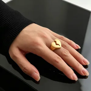Macro detail view of chunky gold-plated broken heart ring worn on a woman's hand