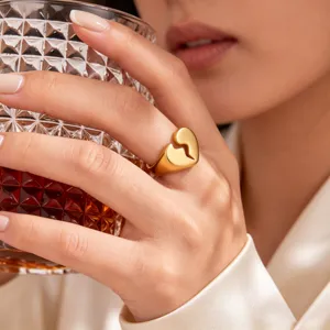 Detailed close-up of a gold-plated stainless steel broken heart signet ring on a hand.