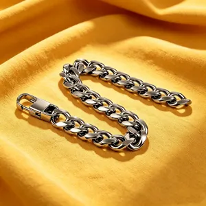 Close-up of polished stainless steel Cuban link bracelet on yellow fabric background