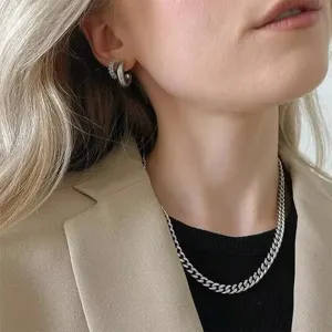 Close-up of a silver-toned stainless steel Cuban link necklace worn by a female fashion model