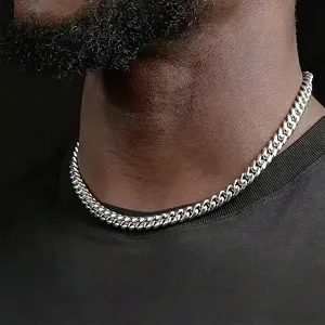 Detailed close-up showing a polished silver-tone Cuban link chain necklace on model neck