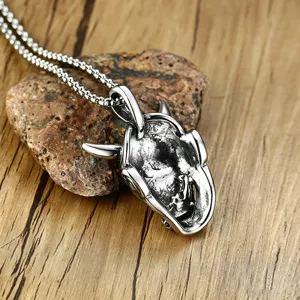 Detailed close-up of a vintage distressed silver Hannya mask pendant on a box chain