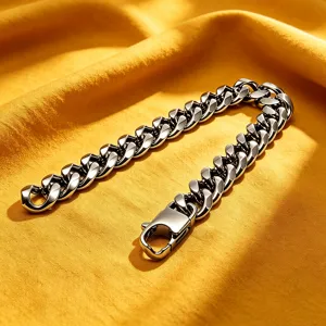 Macro view of a heavy stainless steel Cuban link bracelet for men on textured yellow fabric.