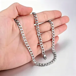 Détail de la texture d'un collier à mailles cubaines en acier inoxydable argenté tenu à la main