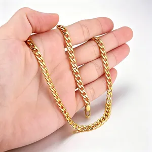 Détail d'un collier à maillons cubains en acier inoxydable doré tenu à la main