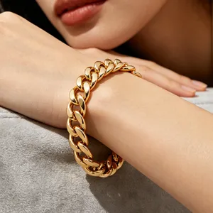 Close-up of a chunky gold-plated stainless steel Cuban link bracelet worn on a wrist.
