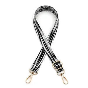 Bandoulière de sac géométrique noire et blanche réglable avec crochets dorés.