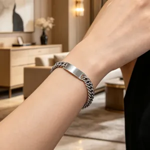 Close-up of polished stainless steel Cuban link bracelet with blank ID plate on wrist.