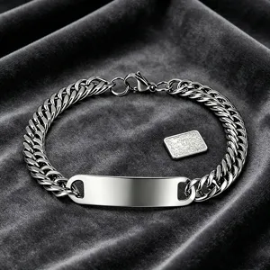 Detailed macro view of a polished stainless steel Cuban link bracelet with a blank ID tag