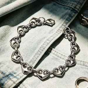 Vista dettagliata di un bracciale a maglie a cuore in acciaio inox su sfondo di jeans