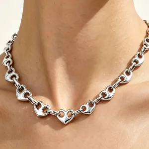 Close-up of a silver stainless steel hollow heart chain necklace on a model's neck