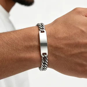 Detail of a men's polished stainless steel Cuban link bracelet with a blank ID plate.
