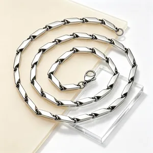 Close-up of silver-tone stainless steel rhombus link necklace on acrylic blocks