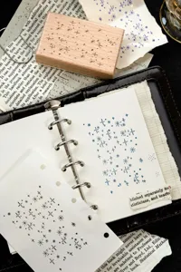 Close-up of a beech wood stamp with starry patterns on a vintage binder and book pages.