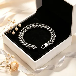 Close-up view of a polished stainless steel Cuban link bracelet in a white jewelry box.