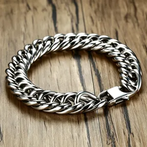Detailed view of a thick silver Cuban link bracelet on a textured wooden background.