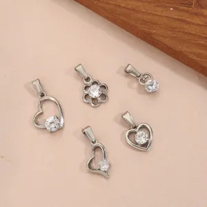 Detailweergave van diverse hart- en bloemhangers in zilver met fonkelende kristallen.