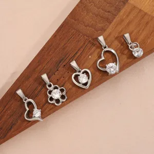Detailopname van vintage zilveren hart- en bloemhangers met heldere kristallen op houtdecor