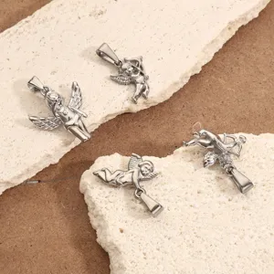 Four stainless steel Cupid angel wing pendants displayed on a textured stone surface