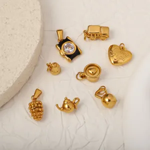 Macro detail of various 18k gold plated stainless steel charms on white textured paper