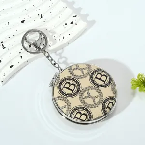Macro view of portable mini folding mirror keychain with elegant B pattern