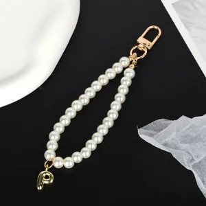 Elegant close-up of a white pearl keychain featuring a gold initial P charm and clasp