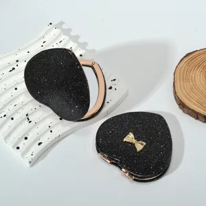 Detailed view of heart-shaped glitter black compact mirror with gold bow decoration