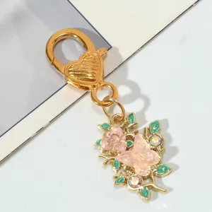 Close-up of golden heart-clasp keychain featuring a pink rose and butterfly charm