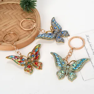 Close-up of three butterfly keychains with colorful rhinestones on a white background.