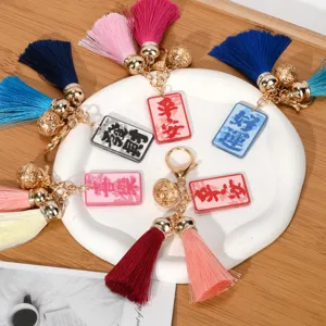 Close-up view of colorful tassel keychains featuring golden bells and Chinese blessing charms