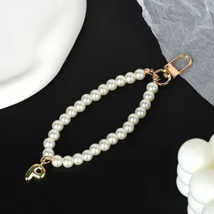 Macro detail of elegant white pearl strap featuring a gold-plated letter P charm and clasp