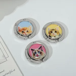 Macro view of three foldable metal purse hooks featuring charming pet cat portrait designs
