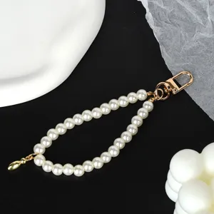 Close-up of elegant white pearl phone strap with a shiny gold-plated metal clasp