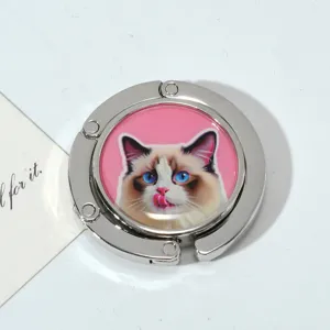 Detailed view of a foldable metal purse hook featuring a cute Ragdoll cat design