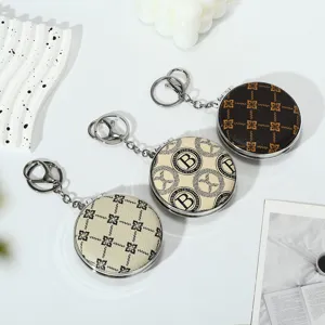 Close-up of portable round folding mirrors with stylish patterns and keychains