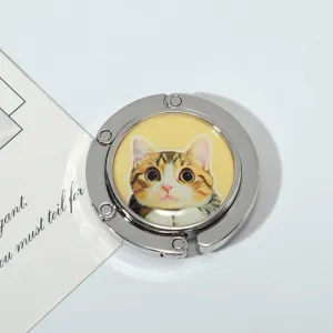 Detailed close-up of a portable folding metal bag hook featuring a cute cat pattern design