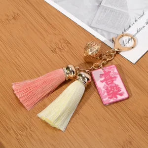 Detailed view of the golden hollow bell and pink tassels on a decorative keychain