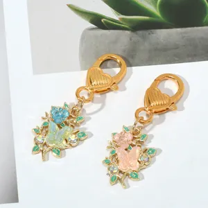 Detailed view of floral and butterfly enamel keychains with gold heart-shaped clasps.